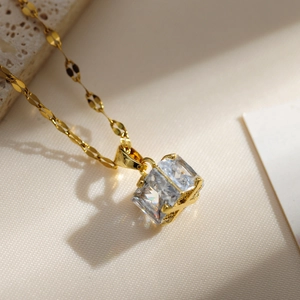 Elegant gold necklace with square-cut crystal pendant on a decorative link chain