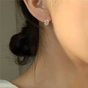 Close-up of minimalist 925 silver four-prong stud earring with zircon on ear model