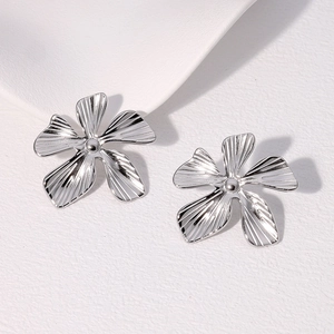 Detailed macro shot of silver flower earrings with fine linear textures and 18K gold plating