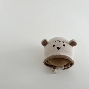Close-up of knit texture and embroidered bear face on winter baby hat with earflaps