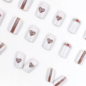Press-on nails featuring hollow heart designs, glitter patterns, and colorful rhinestones