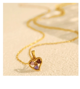 Macro view of a gold hollow heart pendant featuring pink, purple, and brown gemstones