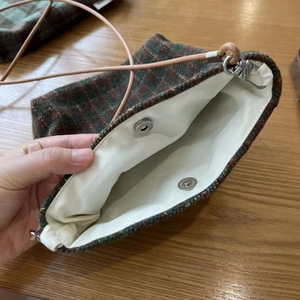 Detail of plaid tweed crossbody bag with canvas lining and magnetic silver clasp