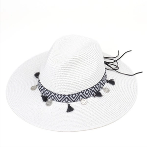 Detail of white straw sun hat featuring ethnic pattern band and black tassel fringe