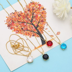 Detail of round gemstone pendants in white, black, red, and blue with gold box chains