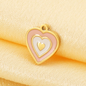 Vue macro d'un pendentif cœur plaqué or 18 carats avec émail rose et blanc sur tissu beige