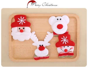 Detailed close-up of plush Santa and reindeer Christmas brooches in a wooden tray