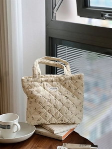 Gros plan d'un sac à main matelassé à fleurs avec étiquette simple wish sur un rebord