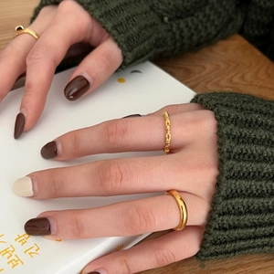 Detailed view of stacked gold twist chain and smooth bands on a model in a cozy setting