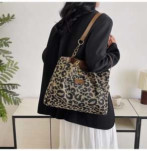 Detail of leopard print tote bag with brown shoulder strap and golden chain accent