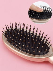 Detail view of champagne gold air cushion massage comb with elastic rubber pad and bristles