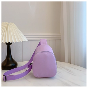 Mini purple nylon chest bag for kids displayed on a marble table with a white lamp