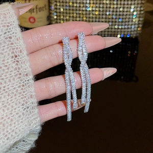 Detail view of silver tassel earrings featuring sparkling rhinestones and twisted design