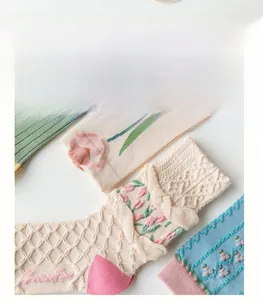 Detail view of cotton socks with floral patterns and ruffled edges in a soft cream palette