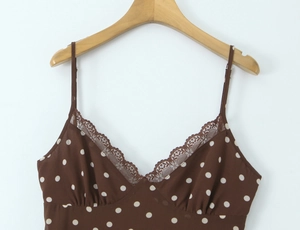 Détail de la bordure en dentelle et motifs à pois blancs sur robe marron sans manches