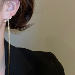 Détail de boucles d'oreilles pendantes dorées avec étoiles en zircon portées par un modèle
