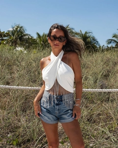 Nahaufnahme des weißen Neckholder-Tops mit silbernen Fransen und blauen Denim-Shorts