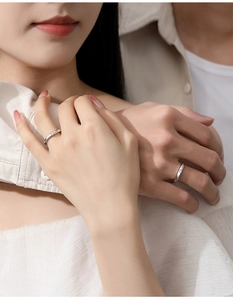 Close-up of minimalist silver couple rings with small diamond inlay on model hands