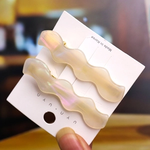 Close-up of wavy leopard pattern hair clips in cream pearlescent resin on white card