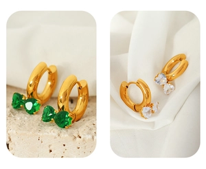 Detail of gold hoop earrings with green and white heart-shaped crystal charms