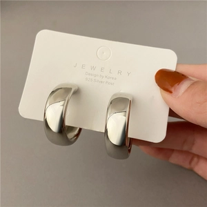Detail of silver-finish C-shape hoop earrings with 925 silver posts on a display card