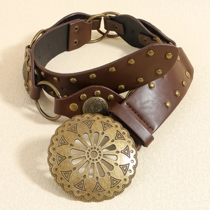 Détail d'une ceinture en cuir marron vintage avec boucle en bronze et rivets décoratifs