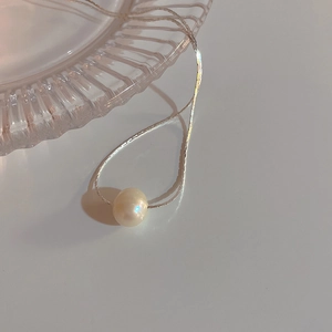 Detail of a lustrous round freshwater pearl pendant on a sleek silver snake chain
