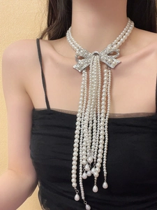 Detail of multi-layer pearl necklace featuring a silver rhinestone bow with long tassels
