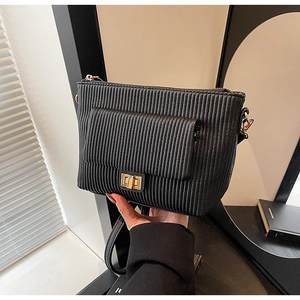 Detail of black vertical pleated shoulder bag with gold metal twist-lock and textured finish
