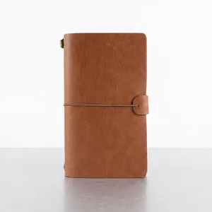 Vintage brown leather traveler notebook with elastic band closure and metal charm
