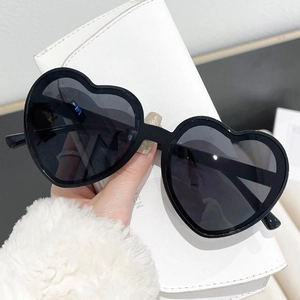 Detail of trendy black heart-shaped sunglasses with dark grey lenses for party wear