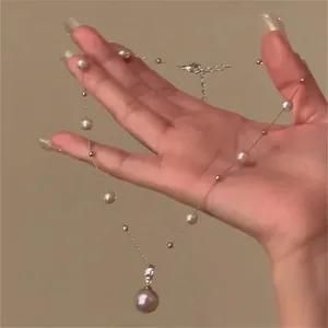 Vue détaillée du pendentif perle en forme de goutte sur une chaîne argentée en main