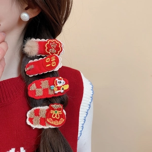 Detail of red New Year hair clips with embroidery and dragon charms on braided hair
