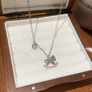 Détail du collier avec pendentif cheval argenté et zircons dans un coffret en bois