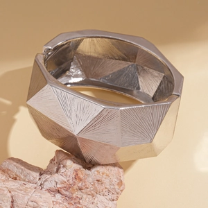 Detailansicht silberner geometrischer Armreif mit strahlentexturierter Metalloberfläche