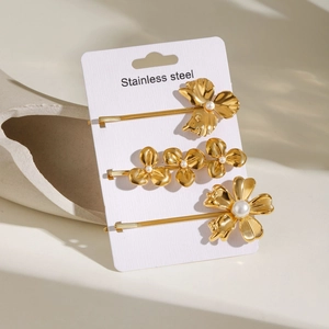 Three-piece set of 18k gold flower pearl hair clips on a minimalist display card