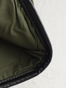 Detail of dark green fabric lining and black faux leather trim with precision stitching