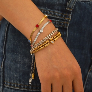 Layered gold and silver zircon bracelets on denim background worn by a female model