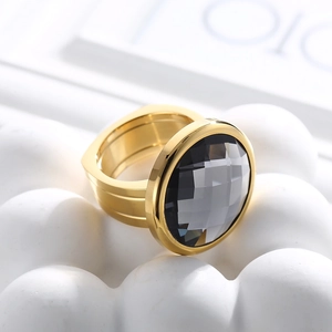 Macro shot of gold-plated cocktail ring with large faceted grey stone on white stand