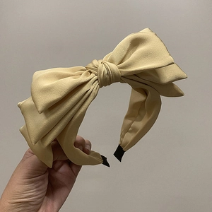 Detail of beige satin headband featuring triple bow design and non-slip inner lining