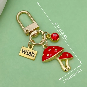 Red enamel mushroom keychain with gold plating, rhinestone charm and wish tag charm
