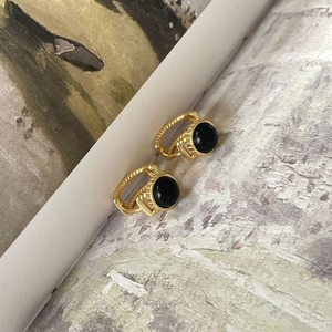 Close-up of gold twist texture hoop earrings with black agate stone inlay