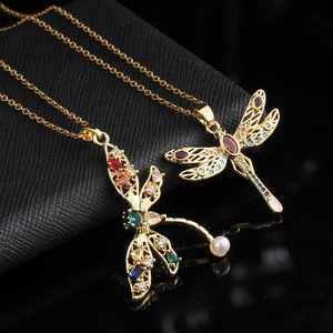 Detailed close-up of dragonfly pendants with colorful crystals and pearl on gold plating
