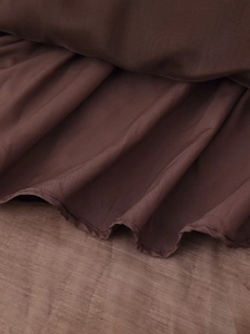 Dettaglio ravvicinato di balze marrone scuro e pieghe sottili sull'abito lungo in chiffon