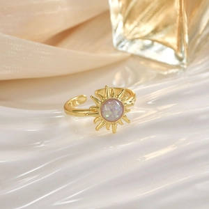 Macro shot of gold sunburst ring featuring a shimmering round opal center on white fabric