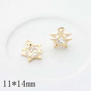 Macro shot of 11x14mm golden star charms with clear zircon inlay on white ceramic tray