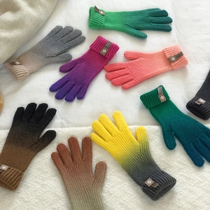 Flat lay of colorful gradient knitted touchscreen gloves on white fabric background