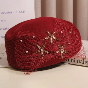 Detailed view of dark red wool beret with elegant mesh veil and pearl embellishments