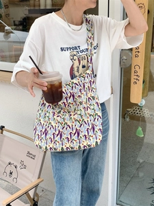 Outdoor shot of a beige floral canvas tote bag with purple and blue flower patterns