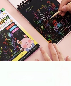 Close-up of children's scratch art notebook with wooden stylus revealing colorful patterns